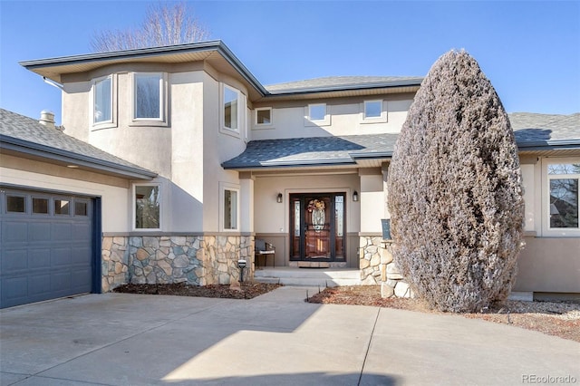 entrance to property with stucco siding, a shingled roof, and concrete driveway