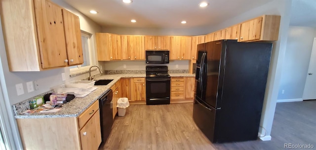 kitchen featuring black appliances, light wood finished floors, a sink, and light brown cabinetry