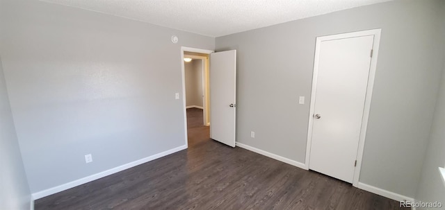 unfurnished bedroom with dark wood-style floors, baseboards, and a textured ceiling