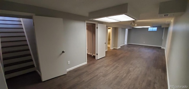 below grade area with dark wood-type flooring, visible vents, and baseboards