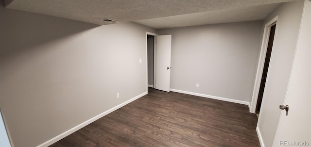 unfurnished bedroom featuring baseboards, visible vents, dark wood finished floors, and a textured ceiling