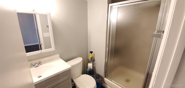 bathroom with toilet, a shower stall, and vanity