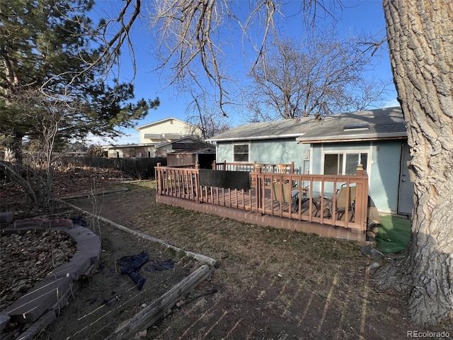 rear view of house featuring roof with shingles, fence, and a wooden deck