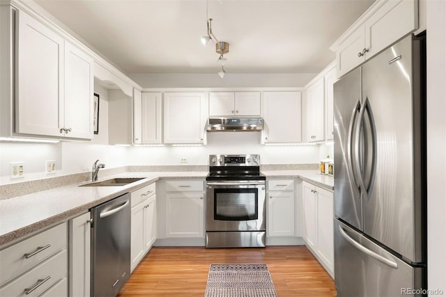 695 S Alton Way Unit 9C, Denver, CO 80247 - kitchen with stainless steel appliances, under cabinet range hood, white cabinets, light countertops, and light wood-style floors