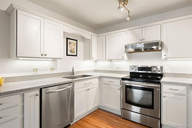 695 S Alton Way Unit 9C, Denver, CO 80247 - kitchen featuring appliances with stainless steel finishes, under cabinet range hood, white cabinetry, light wood-type flooring, and light stone countertops