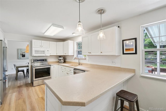 841 Beech St, Golden, CO 80401 - kitchen featuring appliances with stainless steel finishes, light countertops, a peninsula, and light wood-style floors