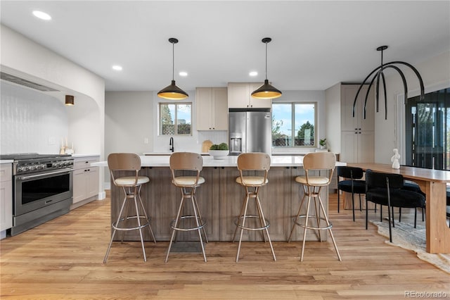 kitchen featuring appliances with stainless steel finishes, light wood finished floors, light countertops, plenty of natural light, and a kitchen island
