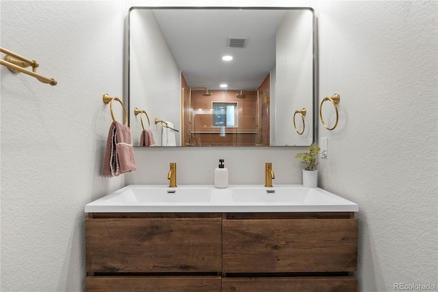 full bathroom with a textured wall, visible vents, a shower, and vanity