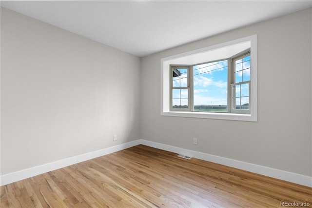 unfurnished room with baseboards, light wood-style flooring, and visible vents
