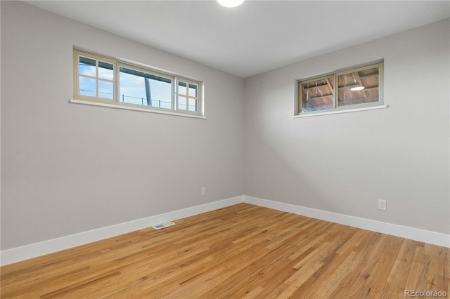 spare room featuring baseboards, light wood finished floors, and visible vents
