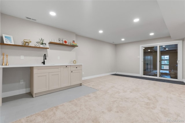 bar featuring light carpet, a sink, baseboards, wet bar, and visible vents