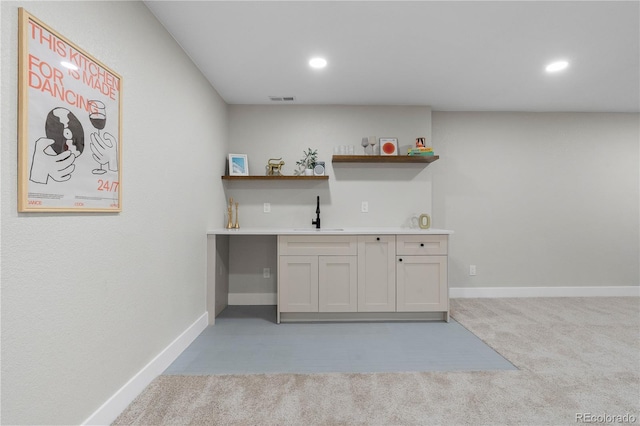 bar featuring visible vents, light carpet, indoor wet bar, baseboards, and a sink