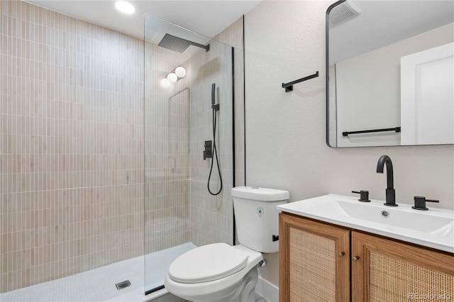full bath featuring vanity, a tile shower, and toilet