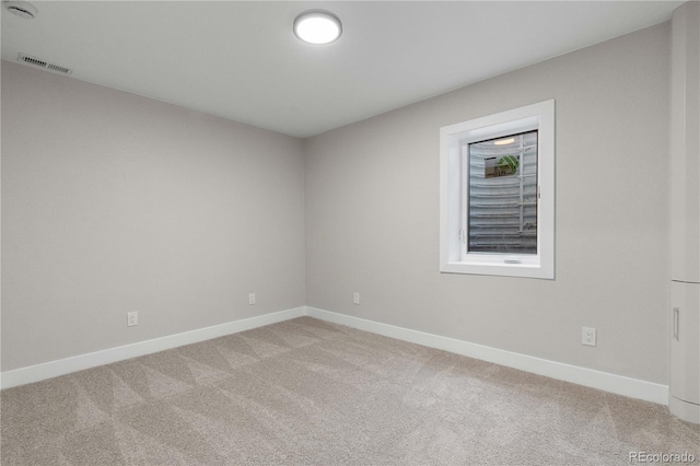 empty room featuring baseboards, visible vents, and light carpet