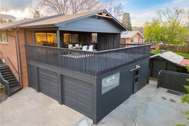 back of property with an outdoor structure, a garage, brick siding, concrete driveway, and a storage shed