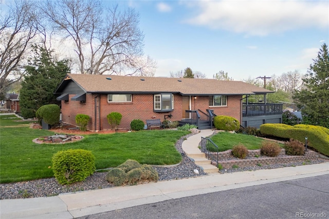 ranch-style house featuring brick siding, a front yard, and roof with shingles