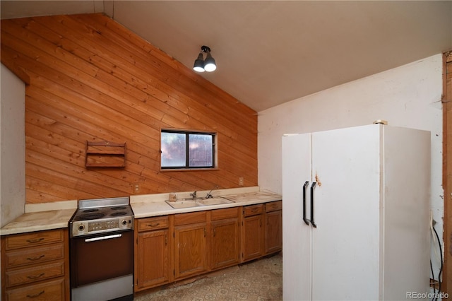 kitchen featuring stainless steel stove, sink, wooden walls, and white refrigerator with ice dispenser