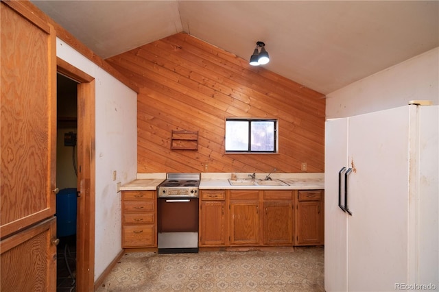 kitchen with white fridge with ice dispenser, sink, vaulted ceiling, wooden walls, and stainless steel stove