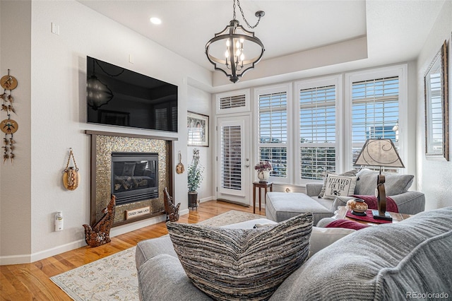 living room featuring light hardwood / wood-style floors, a tile fireplace, and a notable chandelier