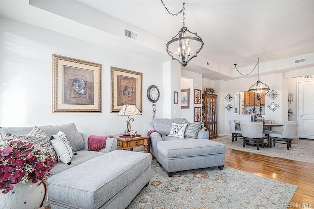 living room with light hardwood / wood-style flooring, a tray ceiling, and a notable chandelier