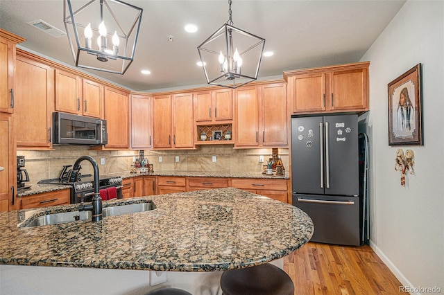 kitchen with pendant lighting, a kitchen bar, sink, a chandelier, and high end fridge