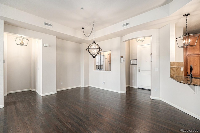 7865 Vallagio Ln Unit 308, Englewood, CO 80112 - unfurnished dining area featuring a chandelier, dark wood-style floors, arched walkways, and a tray ceiling