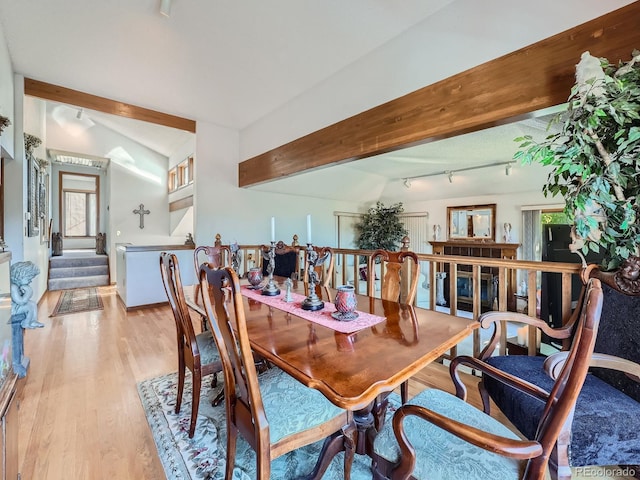 dining space featuring lofted ceiling with beams and light hardwood / wood-style flooring