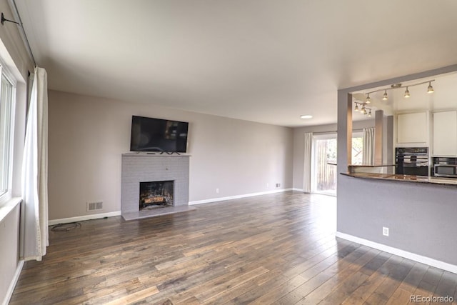 unfurnished living room featuring baseboards, a fireplace, dark wood finished floors, and visible vents