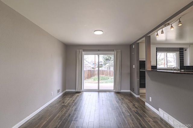 interior space featuring baseboards, a sink, and dark wood finished floors