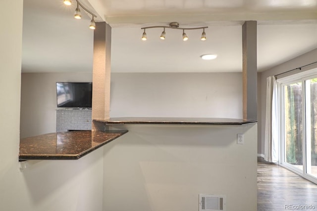 kitchen with visible vents, dark stone countertops, wood finished floors, and track lighting