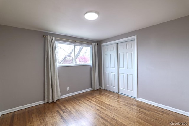 unfurnished bedroom with baseboards, a closet, and wood finished floors