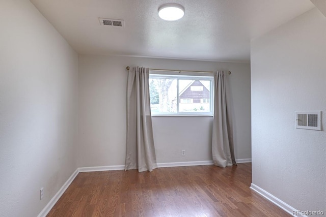spare room featuring visible vents, baseboards, and wood finished floors