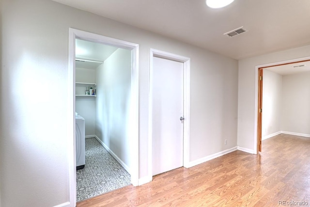 unfurnished bedroom with washer / clothes dryer, baseboards, visible vents, and light wood-style floors