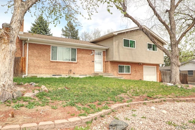 split level home featuring fence, an attached garage, a front lawn, and brick siding