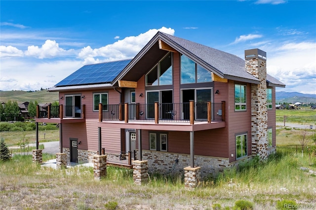251 Grand Elk Way, Granby, CO 80446 - back of property featuring a balcony, solar panels, a chimney, stone siding, and a mountain view