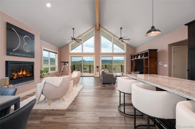 251 Grand Elk Way, Granby, CO 80446 - living room featuring beamed ceiling, a warm lit fireplace, a ceiling fan, wood finished floors, and recessed lighting