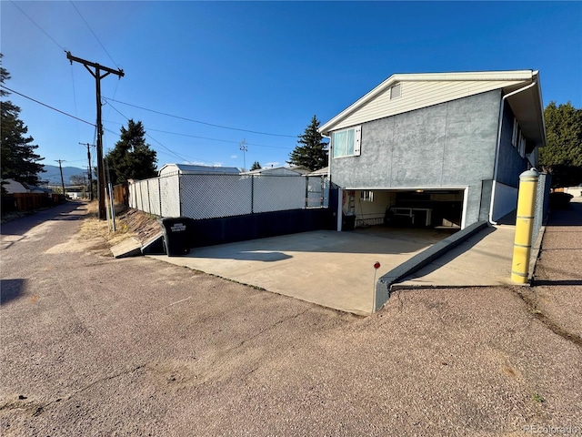 view of home's exterior with fence, a garage, and stucco siding