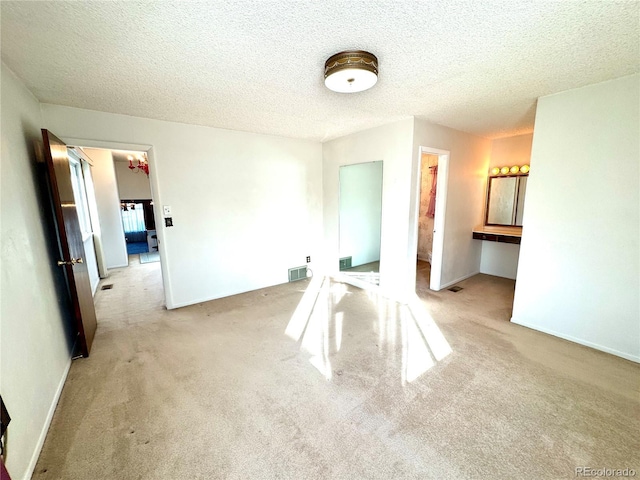 interior space featuring light carpet, a textured ceiling, and visible vents