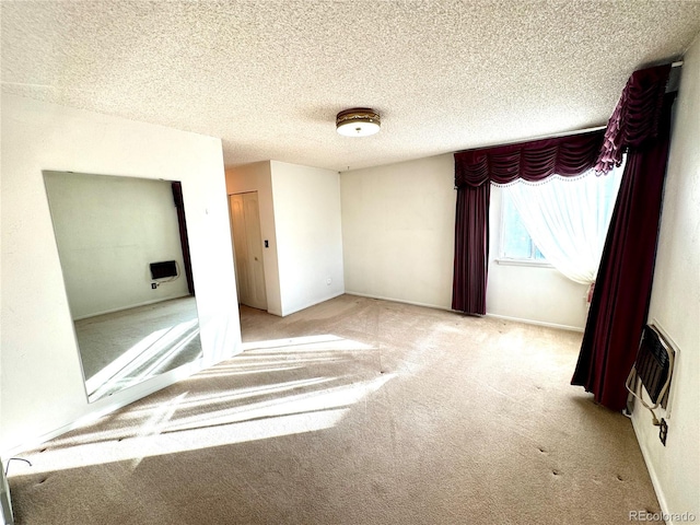 unfurnished bedroom with heating unit, baseboards, carpet floors, and a textured ceiling