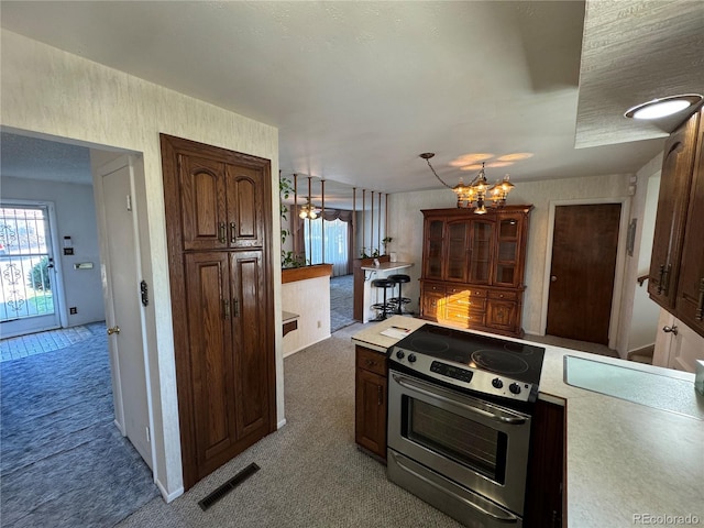 kitchen with stainless steel electric stove, light countertops, visible vents, and carpet flooring
