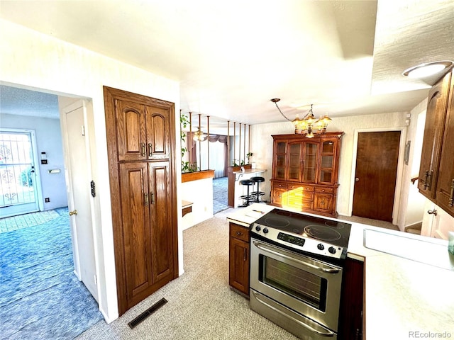 kitchen featuring light colored carpet, stainless steel range with electric stovetop, and visible vents