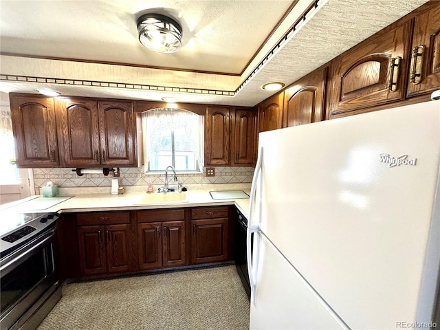 kitchen featuring range with electric cooktop, light countertops, a sink, freestanding refrigerator, and decorative backsplash