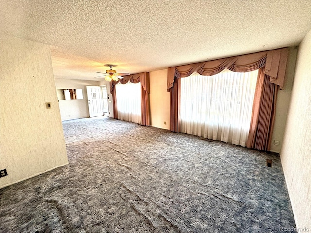 unfurnished room featuring a textured wall, carpet floors, a ceiling fan, and a textured ceiling