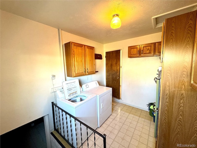 laundry room with washing machine and clothes dryer, baseboards, cabinet space, a textured ceiling, and attic access