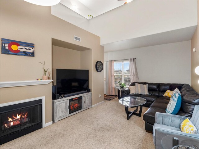 living area with a warm lit fireplace, carpet, and baseboards