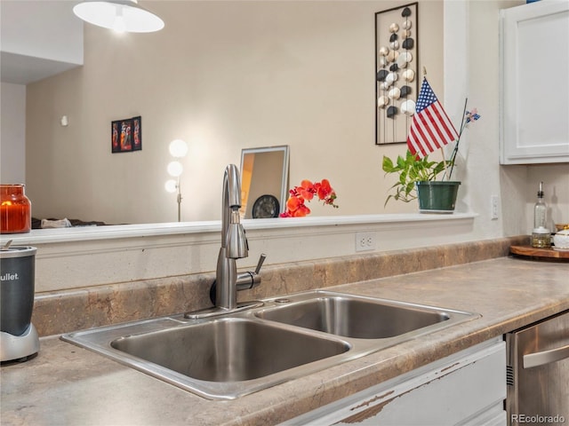 kitchen with a sink, dishwasher, white cabinets, and light countertops