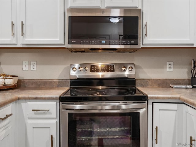 kitchen featuring appliances with stainless steel finishes, white cabinetry, and light countertops