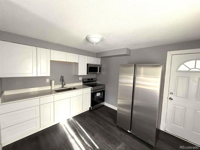 kitchen with white cabinets, appliances with stainless steel finishes, dark hardwood / wood-style flooring, and sink