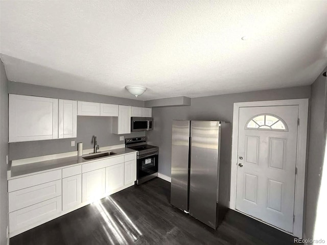 kitchen with dark hardwood / wood-style flooring, a textured ceiling, stainless steel appliances, sink, and white cabinetry