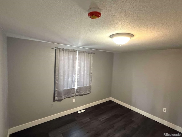 unfurnished room with dark hardwood / wood-style flooring and a textured ceiling